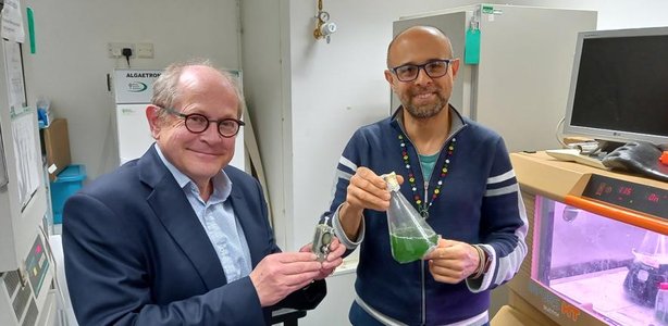 howe-left-holds-algae-device-and-bombelli-right-holds-flask-of-algae